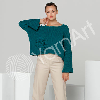 Woman wearing a teal sweater with a floral design on a light gray background