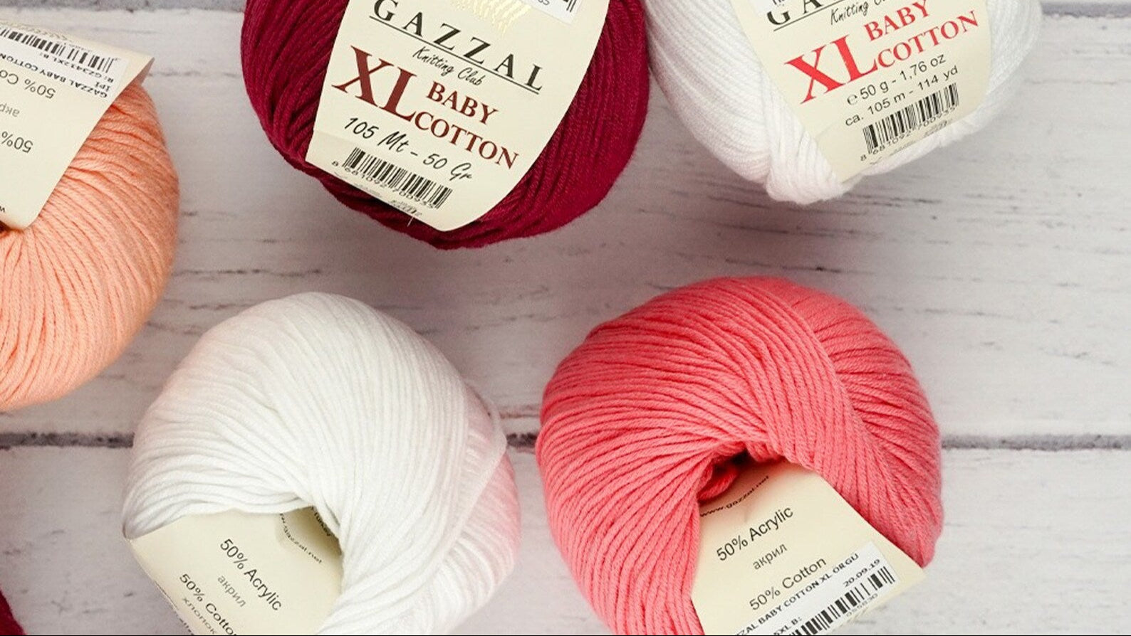 Gazzal Baby Cotton yarn balls in various colors on a wooden surface